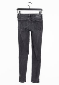 Jeans skinny de mezclilla negra con una textura suave, diseño de cinco bolsillos y un lavado desgastado. Presenta el logo de Calvin Klein en la cinturilla.