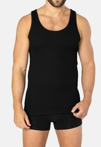 Black ribbed tank top with wide shoulder straps, fitted design, and a soft texture. Worn with matching black shorts.