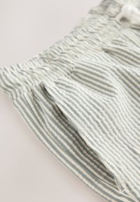 Pantalones cortos a rayas hechos de tela ligera con cintura elástica y cordón. Presentan rayas horizontales en azul y blanco roto.