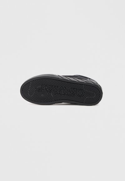 Czarna podeszwa sneakerów z bieżnikiem w jodełkę i wytłoczoną marką "Off-White" na spodzie.