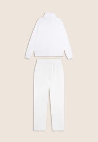 Chaqueta de deporte blanca con cuello alto y mangas largas, acompañada de pantalones con cinturilla elástica a juego. Acabado de tela suave, diseño minimalista.