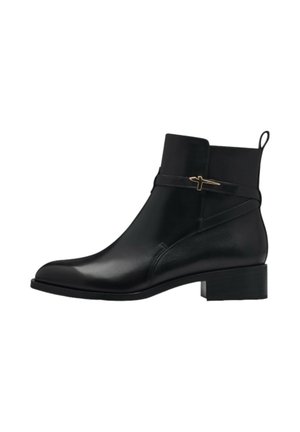 Bottine en cuir noir avec talon bas bloc, sangle décorative et détail en métal doré sur fond blanc.