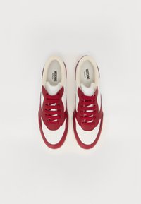 Piros bőr kialakítású, fehér nubukbetétekkel rendelkező sportcipők, kerek orral és texturált fűzőkkel. A logó a talpbetéteken található.