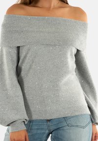 Maglione off-the-shoulder grigio chiaro con collo a coste, impreziosito da paillettes argentate sparse e maniche lunghe leggermente voluminosi.