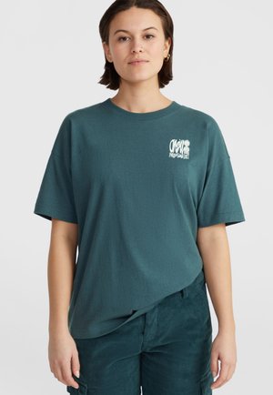 Teal katoenen t-shirt met een ronde hals, korte mouwen en een kleine witte print met tekst en madeliefjes op de bovenste linkerkant van de borst.
