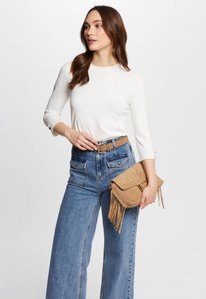 Maglietta bianca a maniche lunghe, jeans in denim blu a vita alta e una borsa a tracolla marrone chiaro con finitura testurizzata. La cintura presenta una fibbia quadrata.