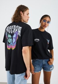 Black cotton t-shirts featuring large butterfly graphic on the back and smaller version on the front, with "FREEDOM" text in bold letters.