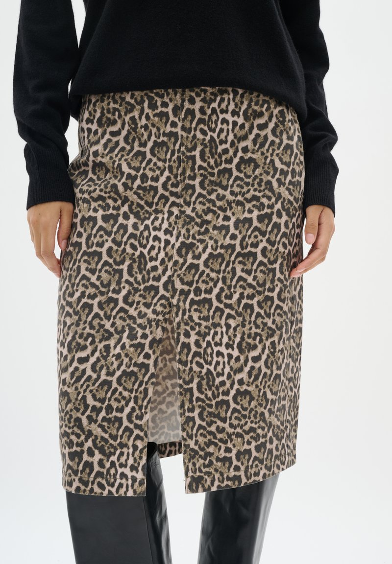 Krilo z leopardjim vzorcem s ravnim krojem, v bež in rjavih odtenkih, z neposredno odprtino spredaj in subtilno teksturo, v kombinaciji s črnima puloverjem.