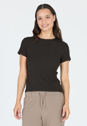 Sort kortærmet ribbet t-shirt med rund hals, parret med beige bukser med snoretræk, præsenteret mod en lys baggrund.