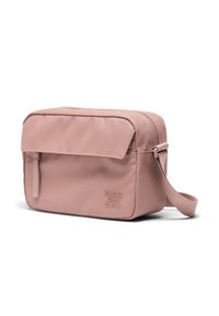 Bolso cruzado de tela rosa con una solapa plana en la parte delantera, cierre de cremallera y una correa lateral. Presenta un logotipo en relieve en la parte frontal.