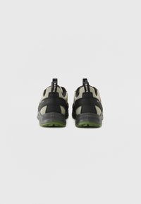 Schwarze und grüne Sneaker mit einem Obermaterial aus Mesh, verstärktem Fersenbereich und Gummisohle. Verfügt über Rückziehhilfen und gekreuzte Riemendetails.