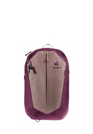 La mochila Deuter presenta un diseño bicolor con la parte inferior en púrpura oscuro y la parte superior en beige claro, tejido texturizado y un bolsillo frontal con cremallera que cuenta con una tira de agarre.