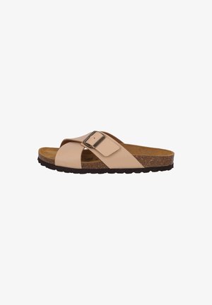 Beige slide sandal with crossover straps, a metallic buckle, cork footbed, and textured rubber sole. Designed for comfort and simplicity.