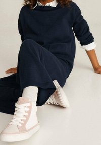 Zapatillas altas blancas y rosas con cordones, combinadas con un conjunto de punto azul marino. La textura parece suave; se ven calcetines hasta el tobillo.