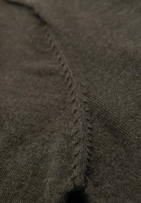 Tessuto a maglia marrone con una texture liscia e dettagli di cucitura visibili. Presenta una leggera lucentezza e un lieve allungamento nel materiale.