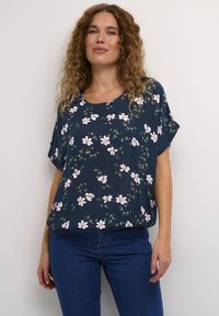 Top navy a fiori con maniche corte, scollo rotondo e vestibilità rilassata, decorato con motivi di fiori rosa e bianchi su un tessuto testurizzato.