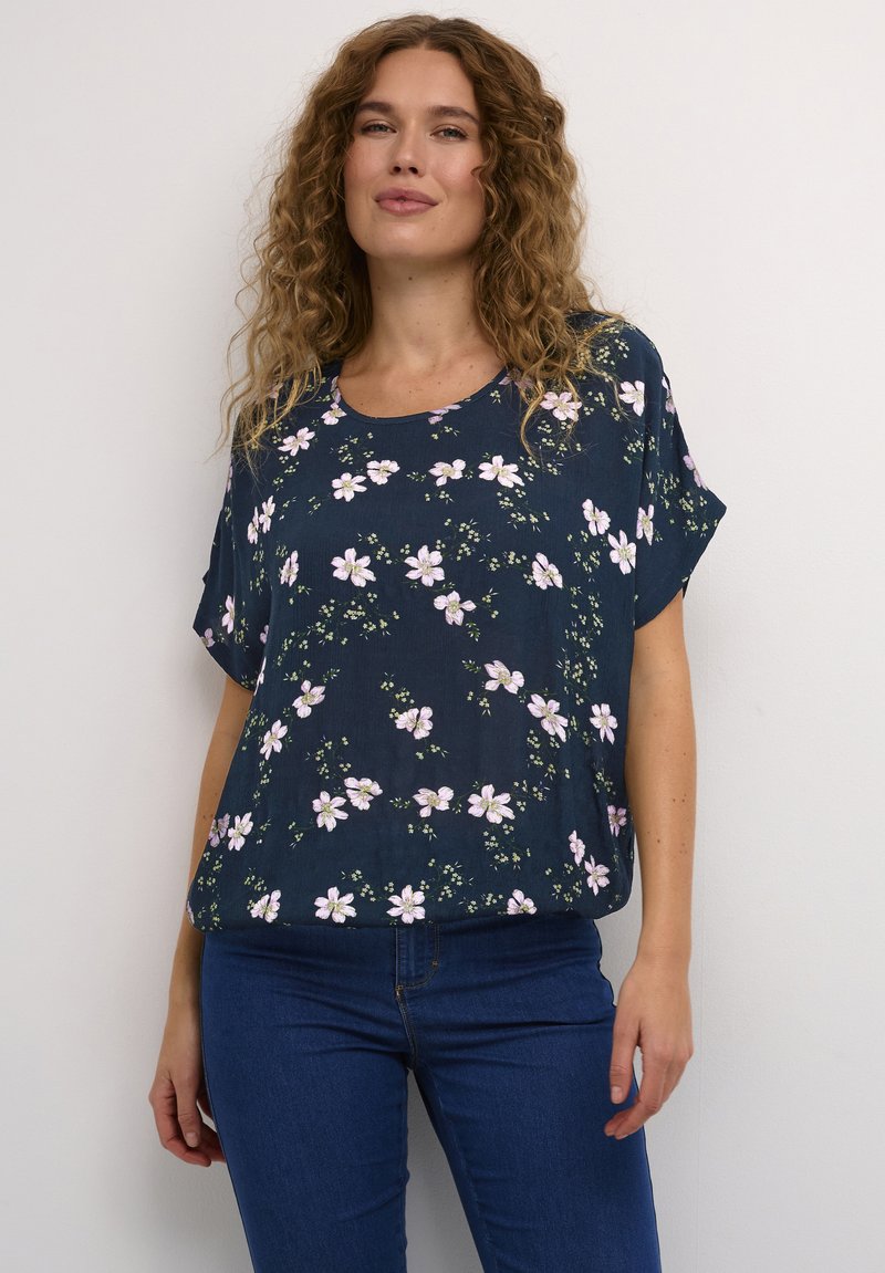 Top navy a fiori con maniche corte, scollo rotondo e vestibilità rilassata, decorato con motivi di fiori rosa e bianchi su un tessuto testurizzato.