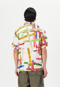 Short-sleeve shirt in lightweight fabric. Multicolored graphic patterns featuring text and symbols on a white background. Relaxed fit.