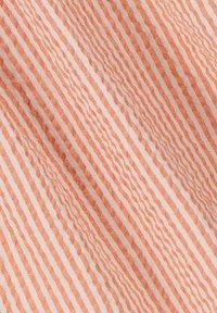 Textiel met afwisselende smalle strepen in zacht perzik en wit, met een golvend textuurpatroon dat visuele interesse toevoegt.