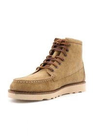 Stivaletti in suede beige con lacci marroni, cuciture da mocassino e suola in gomma di colore chiaro. Resistenti e progettati per il comfort.