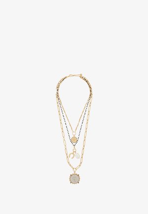 Naszyjnik warstwowy składający się z trzech łańcuszków: złotych metalowych ogniw z czarnymi koralikami, okrągłej ozdobnej zawieszki oraz akcentu z kryształu.