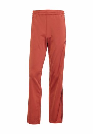 Pantalons de sport rouges pour hommes en tissu lisse, dotés d'une taille élastique, d' fentes latérales et d'accents noirs contrastés sur la poche.
