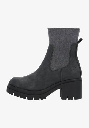 Botte cheville en suede noir avec un revers en feutre gris, épaisse semelle noire et semelle robuste. Elle dispose de panneaux latéraux élastiques et d'une languette pour un enfilage facile.