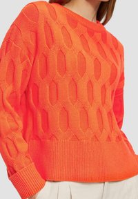 Helles orange gestricktes Sweatshirt mit einem strukturierten Wabenmuster, gerippten Bündchen und Saum sowie einem klassischen Rundhalsausschnitt.