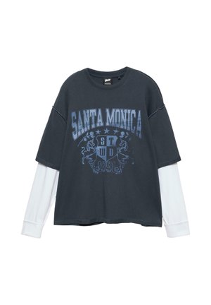 Tricou supradimensionat de culoare gri închis, cu grafică albastră "SANTA MONICA" și emblemă de leu, stratificat cu mâneci lungi albe la manșete. Material din amestec de bumbac.