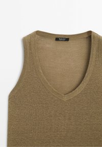 Olivengroen mouwloos gebreid topje met een V-halslijn, met een gladde textuur en een label aan de binnennaad. Zachte, lichte stof.