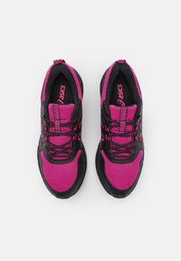 Chaussures de sport noires et roses avec une tige en mesh, un tissu texturé et une semelle noire contrastante. Dotées de lacets et d'un logo sur la languette.