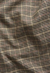 Wool fabric with a houndstooth pattern, featuring beige, black, and burgundy colors. Textured surface with a soft, woven finish.
