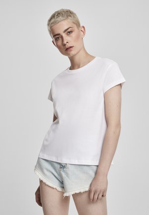 Hvit bomull T-skjorte med korte ermer, rund hals og en løs passform. Kombinert med lyseblå denimshorts med frynset hem.