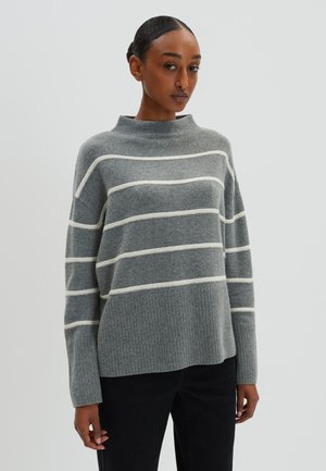 Grau gestreifter Pullover mit hohem Kragen, aus weichem Strickmaterial und mit geripptem Saum. Die Streifen sind cremefarben, was einen Kontrast bildet.