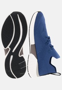Blaue Sportschuhe mit strukturiertem Strickoberteil, runden Schnürsenkeln und einer kontrastierenden braunen Zwischensohle mit einer schwarzen und weißen Gummisohle.