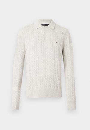 Krémový svetr s pleteným vzorem a límečkem, se třemi knoflíky. Ribbené manžety a lem, na prsou malé logo.