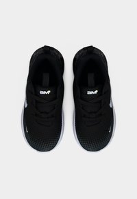 Ζευγάρι αθλητικών παπουτσιών ασπρόμαυρα με κορδόνια και λευκό λογότυπο στη γλώσσα, απεικονιζόμενα από πάνω σε λευκό ομοιόμορφο φόντο.