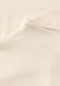 Kremowa, prążkowana tkanina o miękkiej fakturze, z delikatnym streczem i lekkim połyskiem, ukazująca zbliżenie splotu materiału.