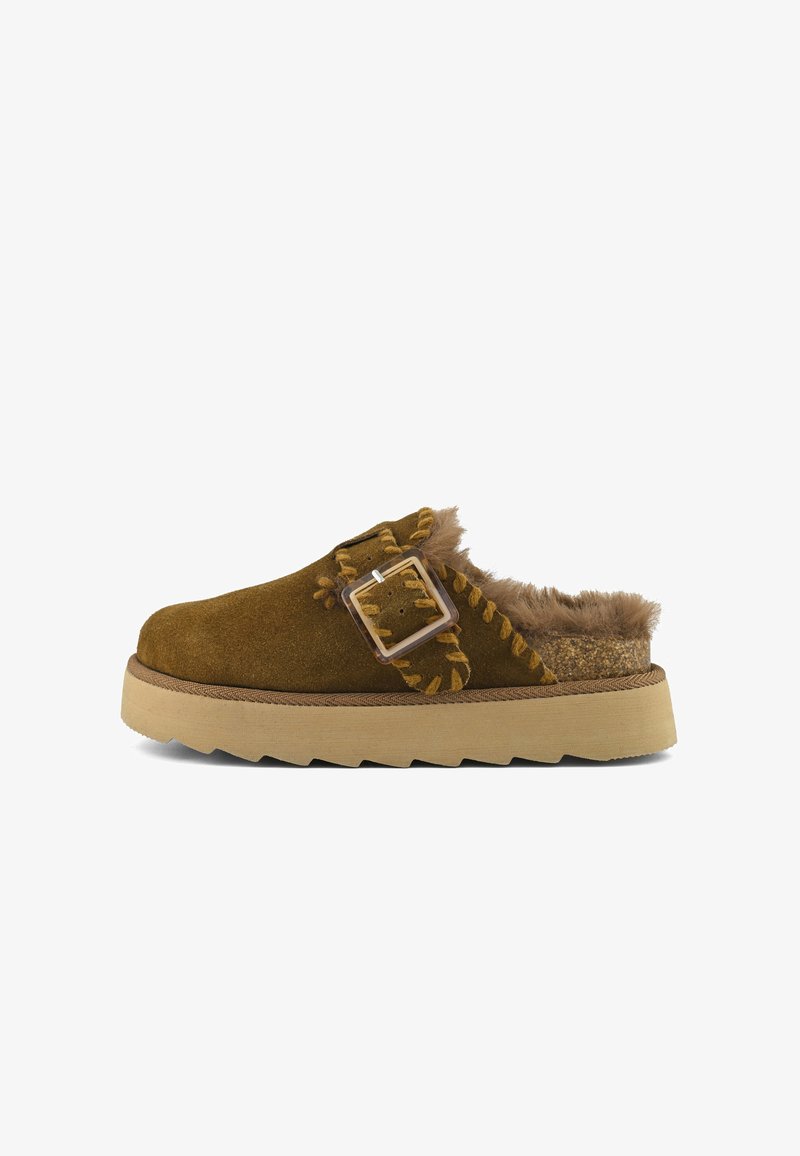 Bruine suede klomp met een fluffy bontaccent, voorzien van een decoratieve gesp en zigzagstiksels. Dikke, gestructureerde zool voor comfort en ondersteuning.