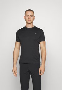Black cotton t-shirt with short sleeves, round neckline, and a small logo on the chest. Fits closely to the body, smooth texture.