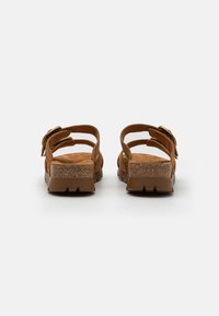 Brune sandaler med åpen bak, to justerbare stropper, teksturert korksåle og flat gummibunn. Har en metallspenne som accent.