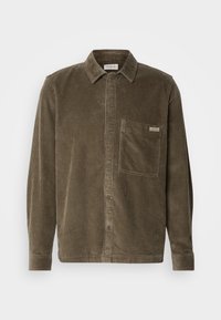 Olive green corduroy shirt jacket with a collar, front buttons, and a chest pocket featuring a small brand label. Long sleeves with cuffs.
