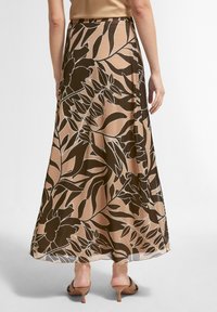 Jupe longue et fluide aux tons marron et beige avec un motif floral. Le matériau semble léger avec une texture lisse, présentant un ourlet droit.