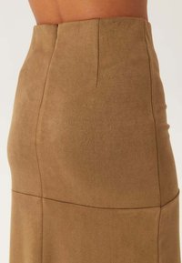 Jupe en daim marron avec une taille ajustée, une texture lisse et une couture qui descend verticalement le long du dos.