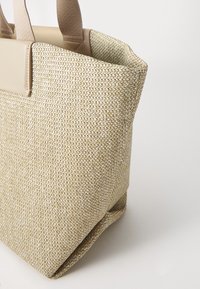 Beige színű szőtt táska struktúrált felülettel, lekerekített sarkakkal és világosbarna szintetikus bőr díszítéssel. Két anyagból készült fogantyúval rendelkezik a hordozáshoz.