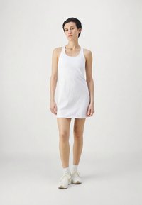 Vit ärmlös klänning med rak skärning, tillverkad av slät tyg. Har en rund halsringning och slutar ovanför knäna.