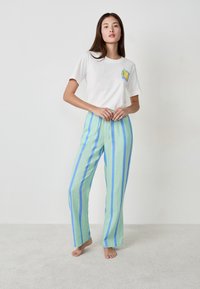 T-shirt bianca con grafica di limone e pantaloni a righe verde-blu realizzati in un tessuto leggero e traspirante con una vestibilità comoda.