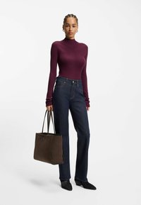 Bordeaux geribbelde coltrui, gecombineerd met donkerblauwe rechte jeans. Bruine suède totebag en zwarte puntige schoenen. Eenvoudig ontwerp en texturen.