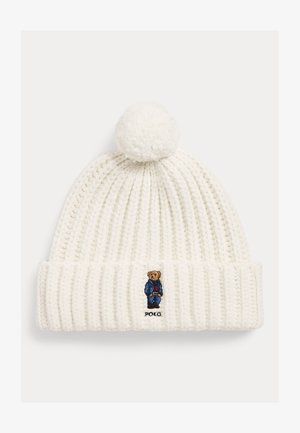 Witte gebreide muts met pompon, met een kleine geborduurde beer in een blauwe outfit en de tekst "POLO" op de omslag.