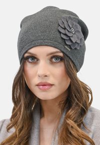 Cappello di lana grigio con finitura testurizzata, caratterizzato da un grande fiore in feltro stratificato e una piccola etichetta metallica del marchio sul lato.